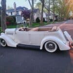 Vintage white convertible on suburban street at sunset