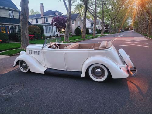 Vintage white convertible on suburban street at sunset