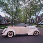 Vintage convertible parked on tree-lined suburban street at sunset