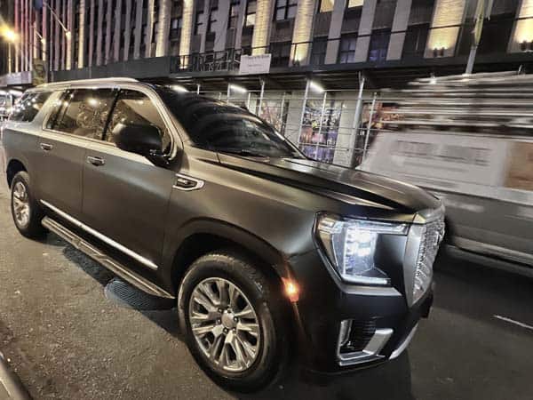 Black SUV parked on city street at night