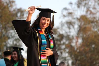 Smiling graduate holding diploma in cap and gown