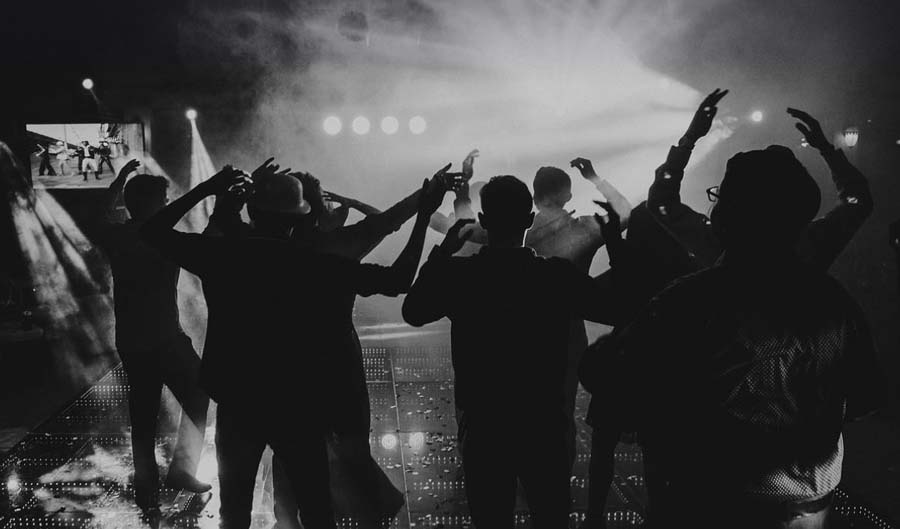 Silhouettes dancing under bright stage lights at party