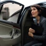 Businesswoman exiting car holding folder