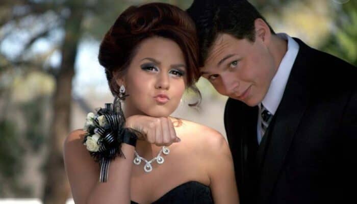 Young couple dressed formally posing at prom outdoors