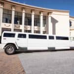 White stretch limousine parked outside luxury mansion