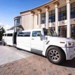 White stretch Hummer limousine parked outside luxury building