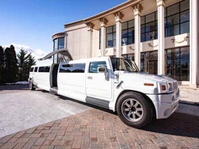 White stretch Hummer limousine parked outside luxury building