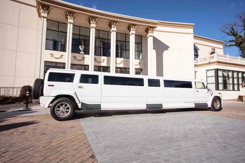 White stretch limousine parked outside luxury mansion