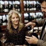 Man pouring red wine for couple in wine shop