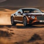 Luxury coupe driving on dusty desert road at sunset