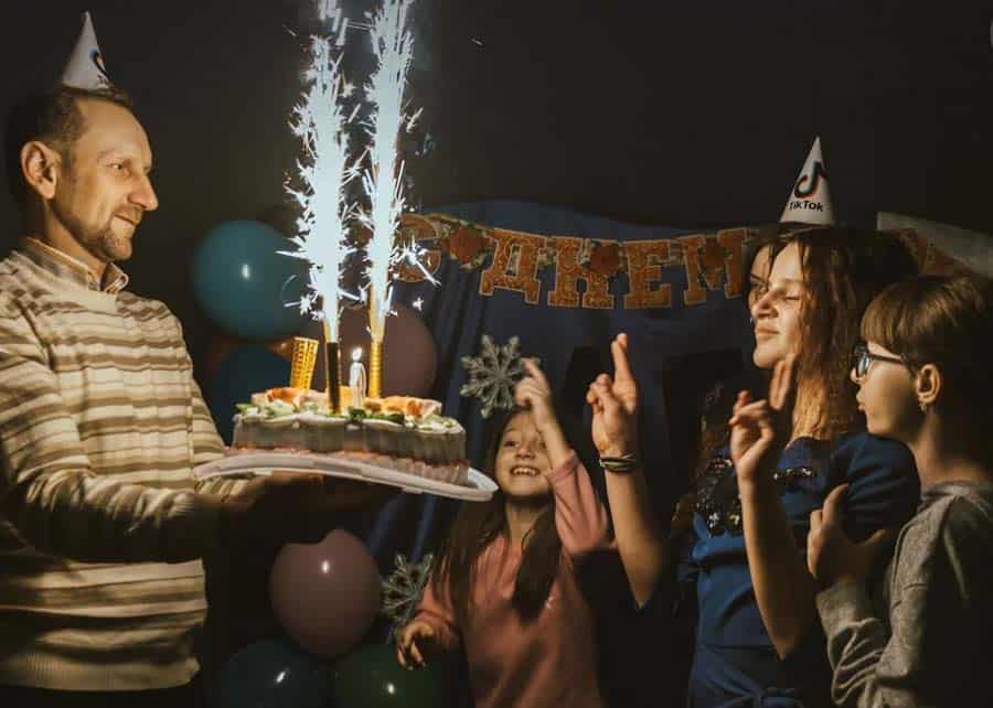 Family celebrating birthday with cake and sparklers indoors