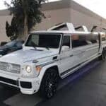 White stretch Mercedes G-Class limousine parked outside building