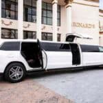 White stretch limousine with open doors outside building