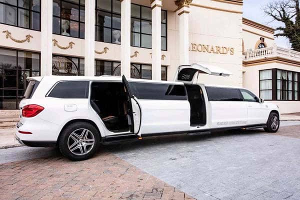 White stretch limousine with open doors outside building