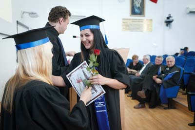 Graduate receiving diploma and rose at ceremony