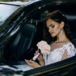 Bride holding bouquet inside car before wedding