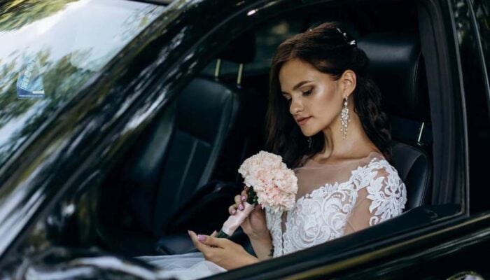 Bride holding bouquet inside car before wedding