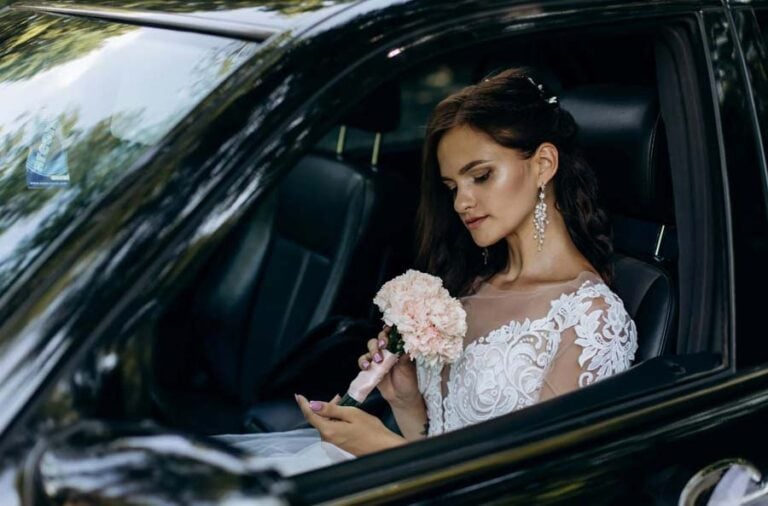 Bride holding bouquet inside car before wedding