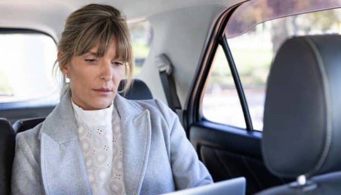 Woman using laptop in backseat of car