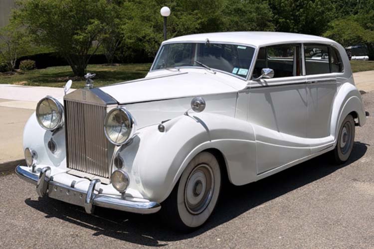 White vintage Rolls-Royce sedan parked on a sunny street