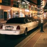 White stretch limousine parked on city street at night