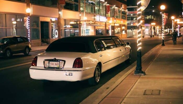 White stretch limousine parked on city street at night