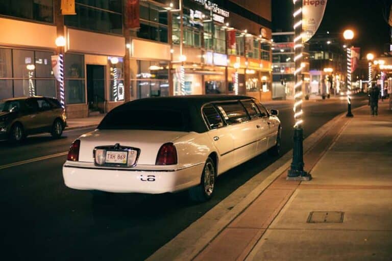 White stretch limousine parked on city street at night