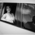 Bride in car window, groom reflected beside her