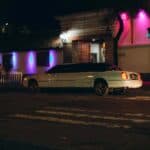 White limousine parked outside neon-lit building at night