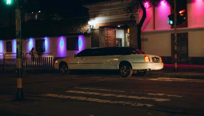 White limousine parked outside neon-lit building at night