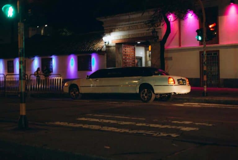 White limousine parked outside neon-lit building at night