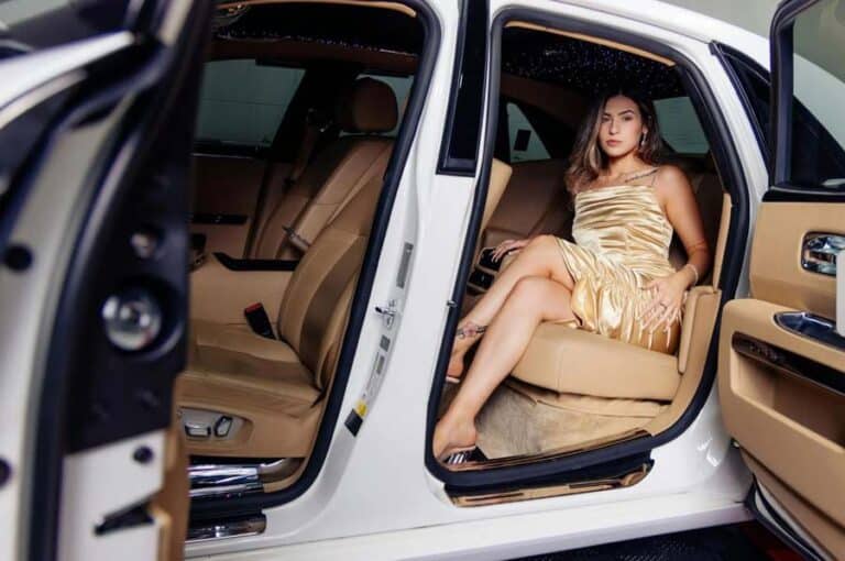 Woman in gold dress sitting in luxury car