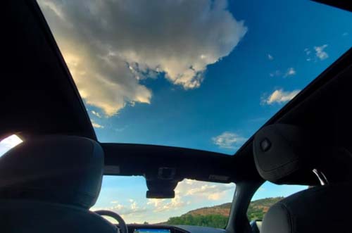Car interior with panoramic sunroof and blue sky
