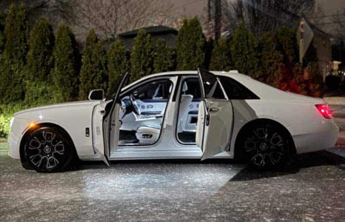 White luxury sedan with open doors at night