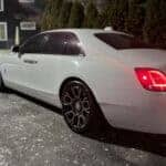 White luxury sedan parked at night, rear view