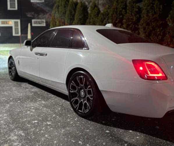 White luxury sedan parked at night, rear view