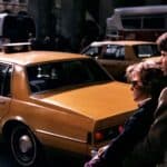 Couple standing beside yellow taxi on city street
