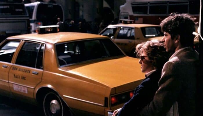 Couple standing beside yellow taxi on city street
