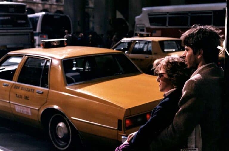 Couple standing beside yellow taxi on city street