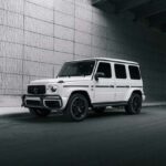 White Mercedes G-Wagen SUV parked under urban overpass.
