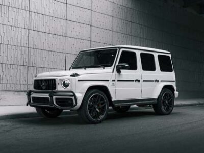 White Mercedes G-Wagen SUV parked under urban overpass.