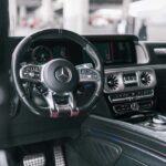Luxury Mercedes car interior with black steering wheel, red seat.