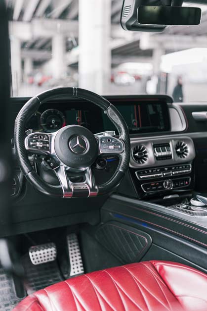 Luxury Mercedes car interior with black steering wheel, red seat.
