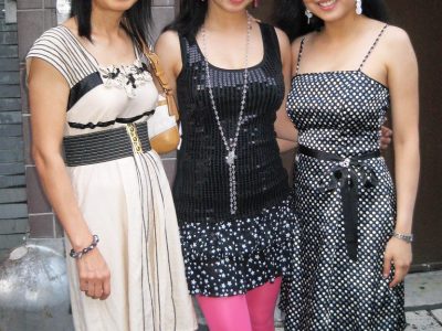 Three women posing together outdoors in dresses