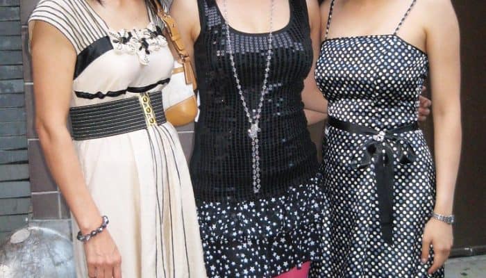 Three women posing together outdoors in dresses