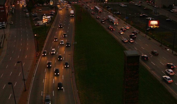 City skyline at sunset with busy highway traffic