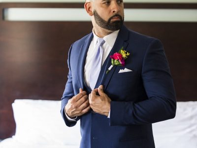 Man in navy suit with boutonniere adjusting jacket