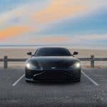 Black sports car parked by beach at sunset
