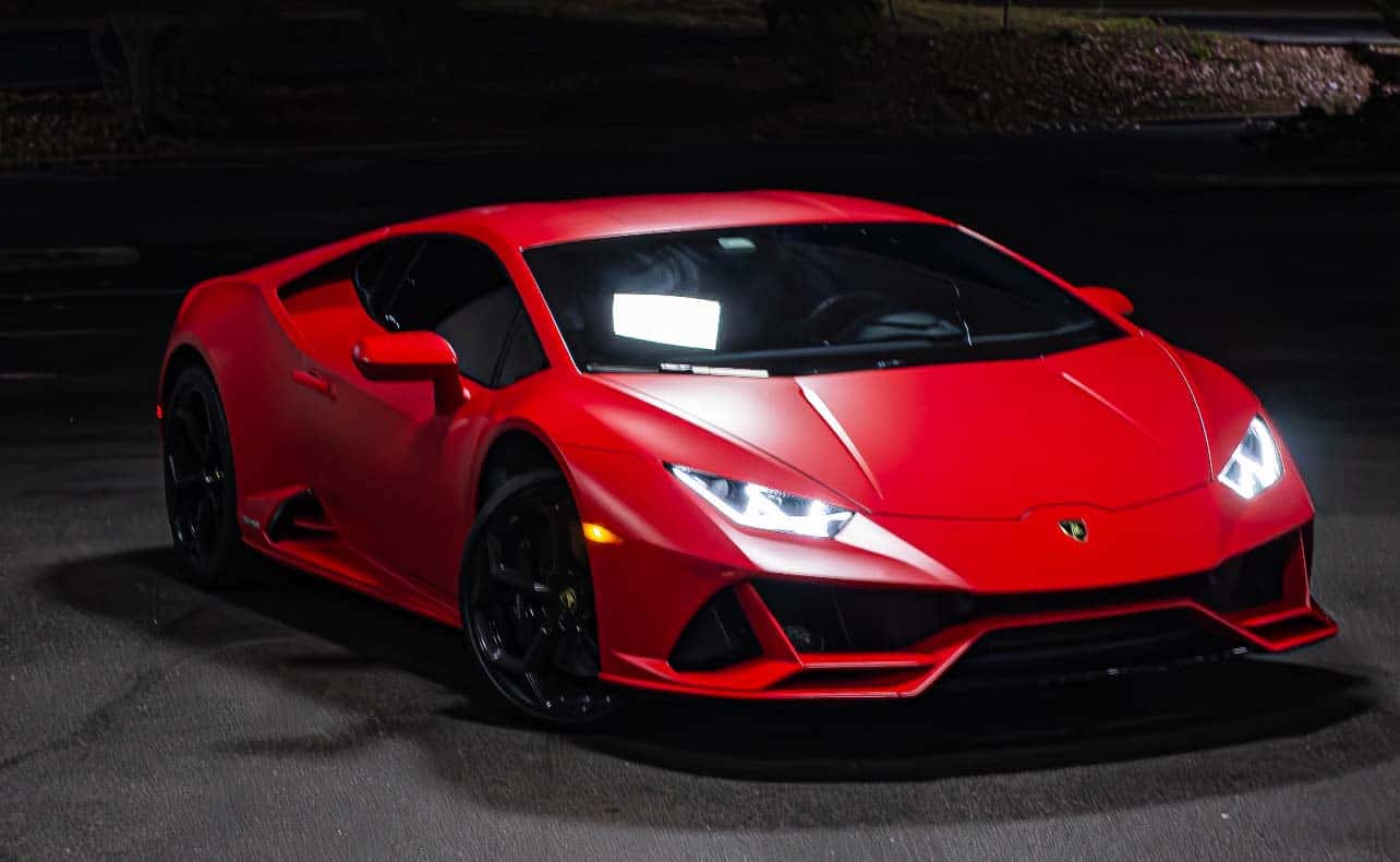 Red Lamborghini sports car with headlights on at night