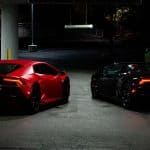 Red and black sports cars parked at night
